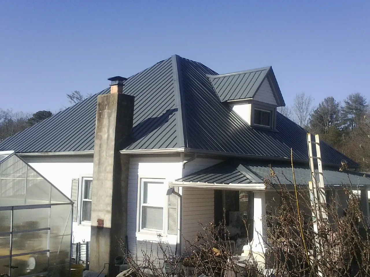 Dark blue standing seam metal roof on a white farmhouse with dormer — Slate & Tile Roof Repair by Roofing Brothers in Palisades