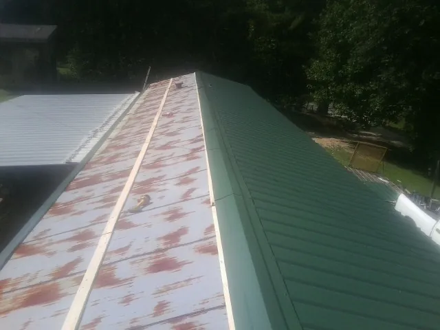 Old rusted panels beside newly installed green metal roofing — Wind Damage Roof Repair by Roofing Brothers in Palisades