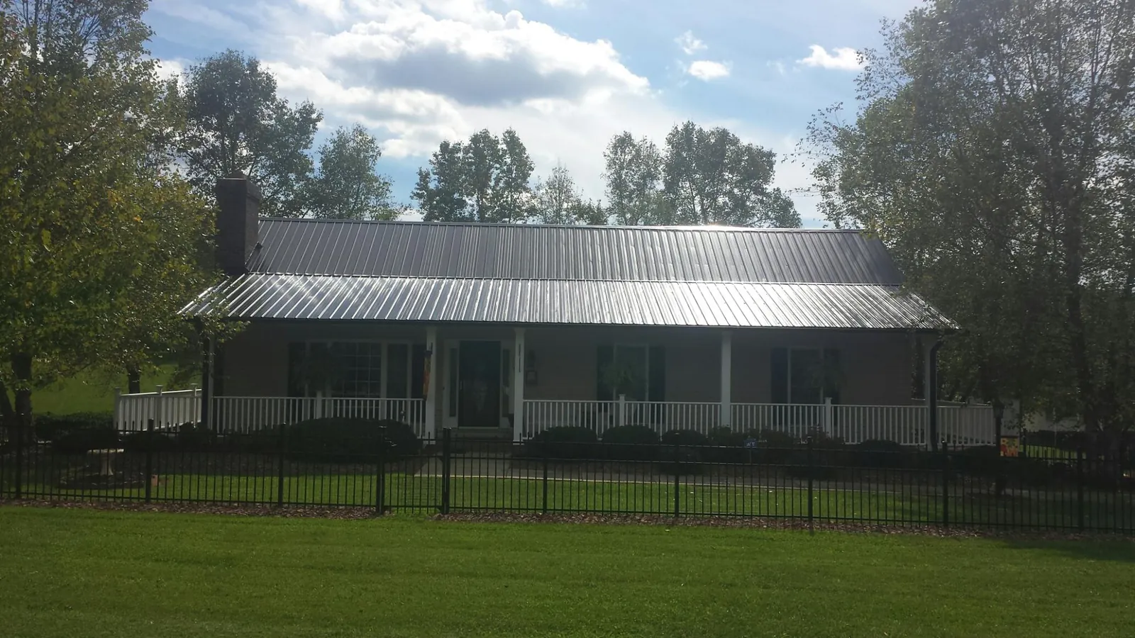 Gray metal roof on a brick ranch with a full width front porch — Gutter Guard Installation work by our crew in Palisades