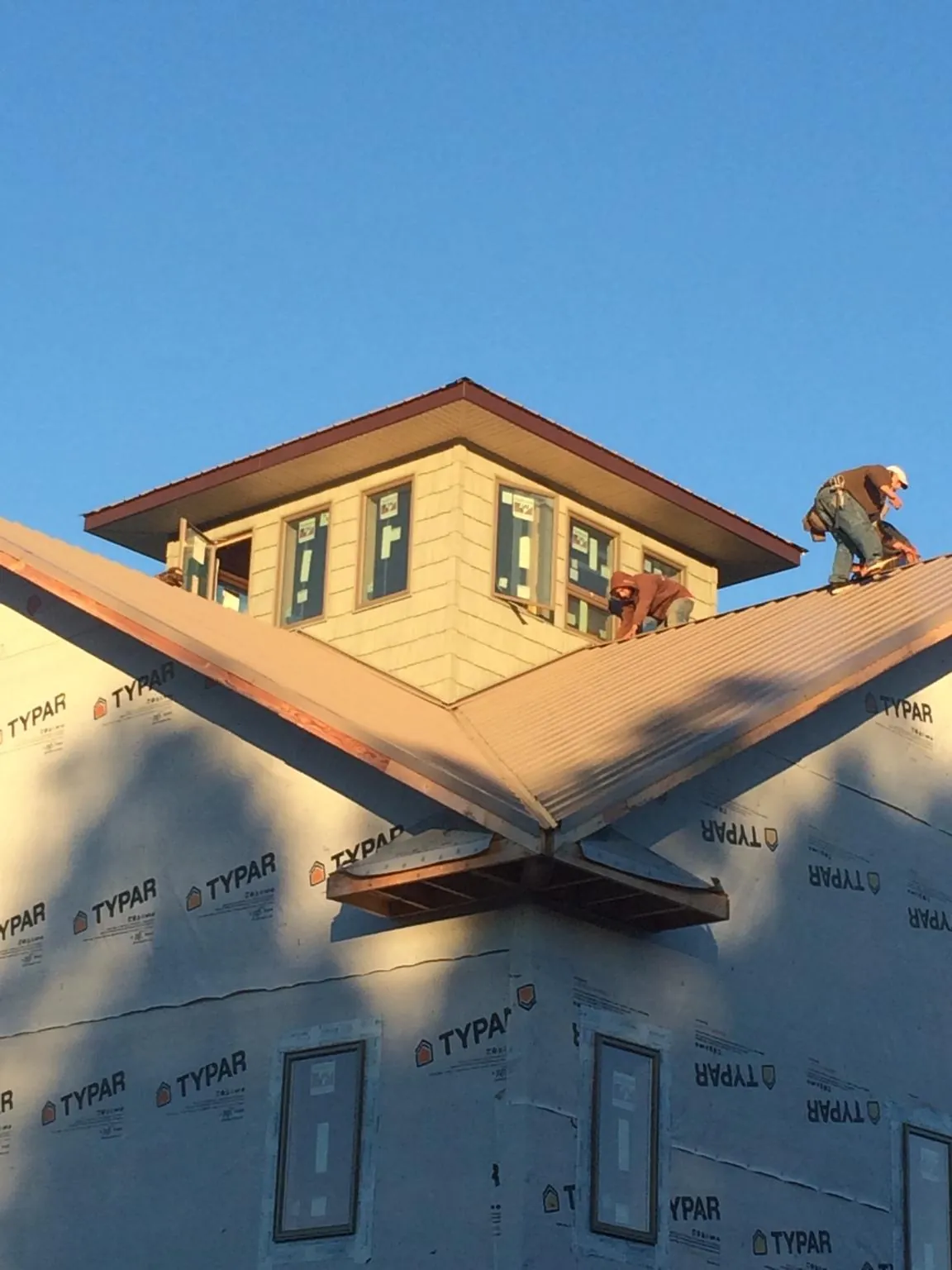 Roofers working around a rooftop cupola on a new metal roof at sunset — Roof Waterproofing in Palisades by Roofing Brothers